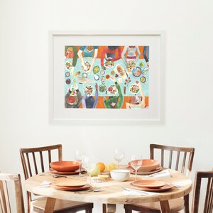 May include: A framed illustration of a group of people gathered around a table, preparing food. The table is covered in a light blue tablecloth and is filled with various dishes, including bowls of salad, plates of food, and a loaf of bread. The people are all wearing different colored clothing and are interacting with each other.