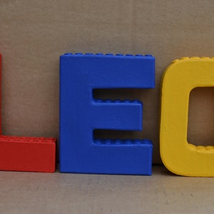 Hand painted papier mache lego letters spelling LEO in red, blue & yellow