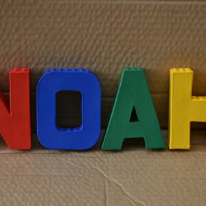 Hand painted papier mache lego letters spelling NOAH in red, blue, green & yellow