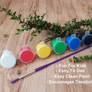 6 different coloured acrylic paints in a strip with a colourful handled childrens paintbrush
