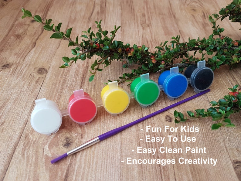 6 different coloured acrylic paints in a strip with a colourful handled childrens paintbrush