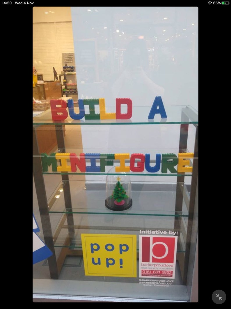 Hand painted papier mache lego letters sign in red, blue, green & yellow in a shop window