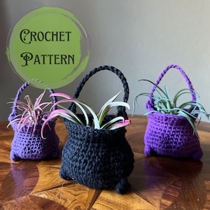 May include: Crochet pattern for a cauldron-shaped planter. Three planters are shown, one black and two purple, each with a green air plant inside. The text "CROCHET PATTERN" is written in a green circle.