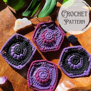 May include: Four crochet hexagon patterns in shades of purple and black, arranged on a wooden surface. The patterns feature spiral designs and are labeled "Crochet Pattern". The image includes a leaf and crystals.