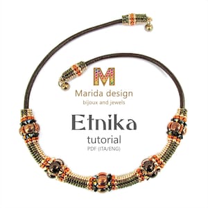 Peut inclure: Un collier en cuir marron avec des perles dorées et brunes, présentant un motif géométrique. Le collier a un petit charme de cloche à chaque extrémité. Le texte "Marida design bijoux and jewels Etnika tutorial PDF (ITA/ENG)" est affiché sur un fond blanc.