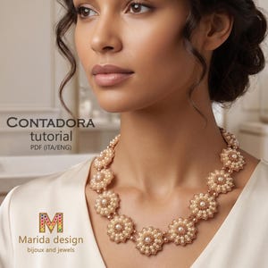 Puede incluir: Un collar de cuentas con una serie de motivos florales interconectados, elaborados con pequeñas perlas de color crema y cuentas de bronce metálico. El texto "CONTADORA tutorial PDF (ITA/ENG)" y "Marida design bijoux and jewels" es visible.