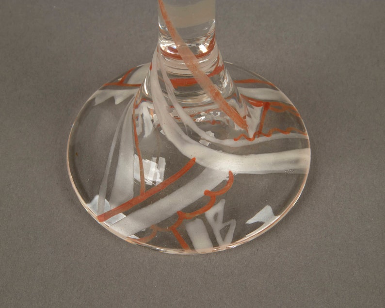 May include: Clear glass goblet with a white and orange swirl design on the base.