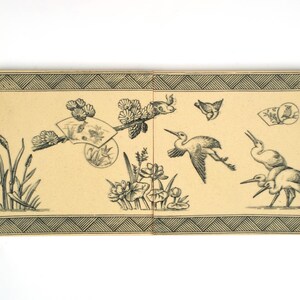 May include: A rectangular beige panel featuring black ink illustrations of birds, lotus flowers, and reeds. The design includes a decorative geometric border at the top and bottom, with a central fan motif and several cranes depicted in flight.