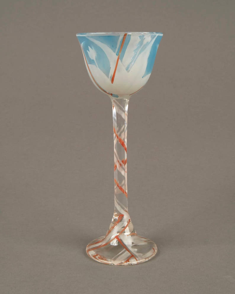May include: A tall, clear glass goblet with a wide, flared bowl. The bowl is decorated with a blue and white swirl pattern, and the stem is decorated with a red and white swirl pattern.