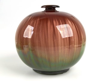May include: A round ceramic vase with a brown and green iridescent glaze. The vase has a wide mouth and a narrow neck.