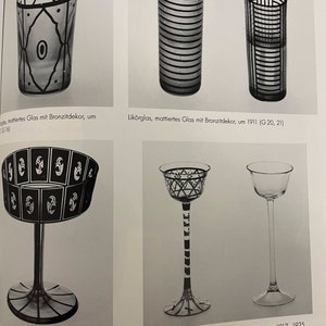 May include: Four different glass cups with black and white geometric designs. The cups are made of frosted glass and have a variety of shapes and sizes. The text on the page reads "Lik&ouml;rglas, mattiertes Glas mit Bronzitdekor, um 1911 (G20, 21)" and "Lik&ouml;rglas, undekoriert, Lik&ouml;rglas mit Emaildekor, um 1917-1925 (G49)"