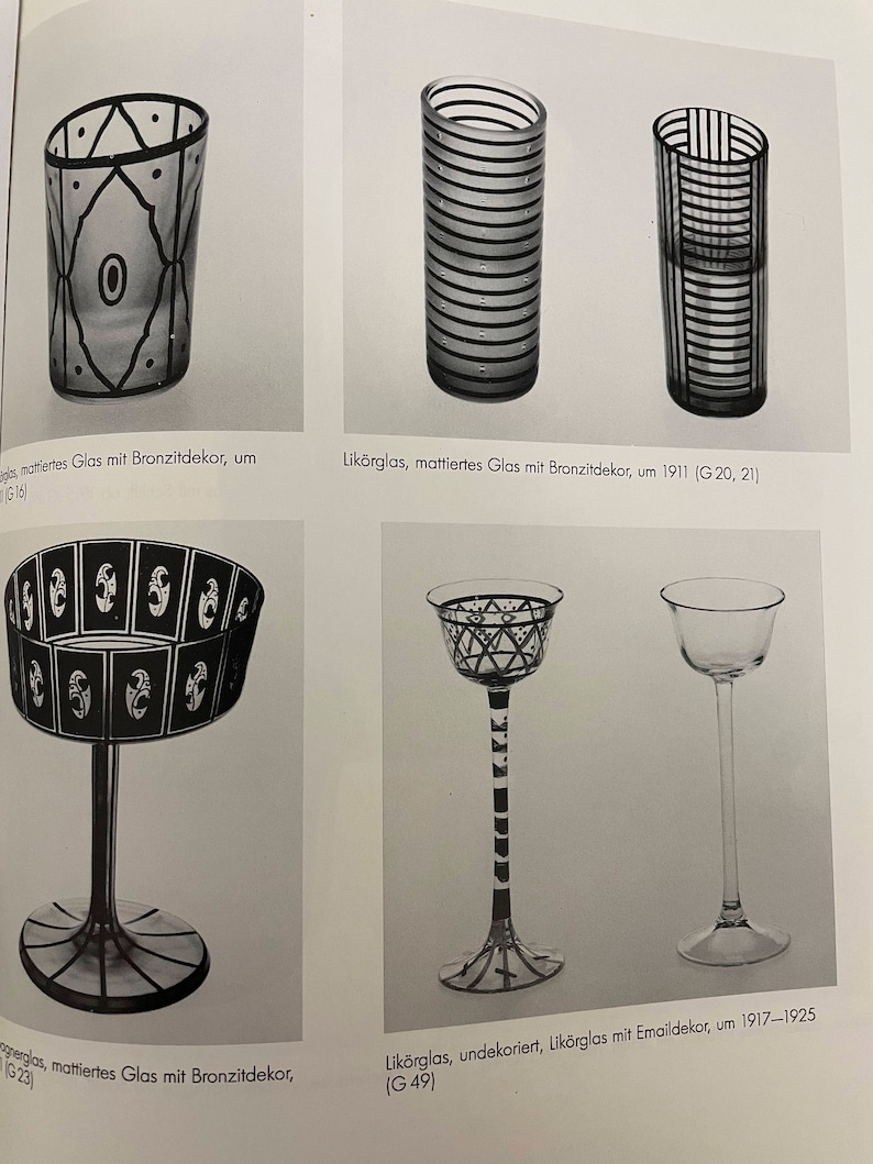 May include: Four different glass cups with black and white geometric designs. The cups are made of frosted glass and have a variety of shapes and sizes. The text on the page reads "Lik&ouml;rglas, mattiertes Glas mit Bronzitdekor, um 1911 (G20, 21)" and "Lik&ouml;rglas, undekoriert, Lik&ouml;rglas mit Emaildekor, um 1917-1925 (G49)"