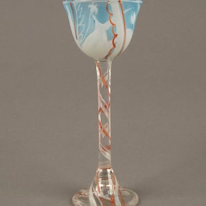 May include: A tall, clear glass goblet with a blue and white design on the bowl and a red and white swirl pattern on the stem and base.