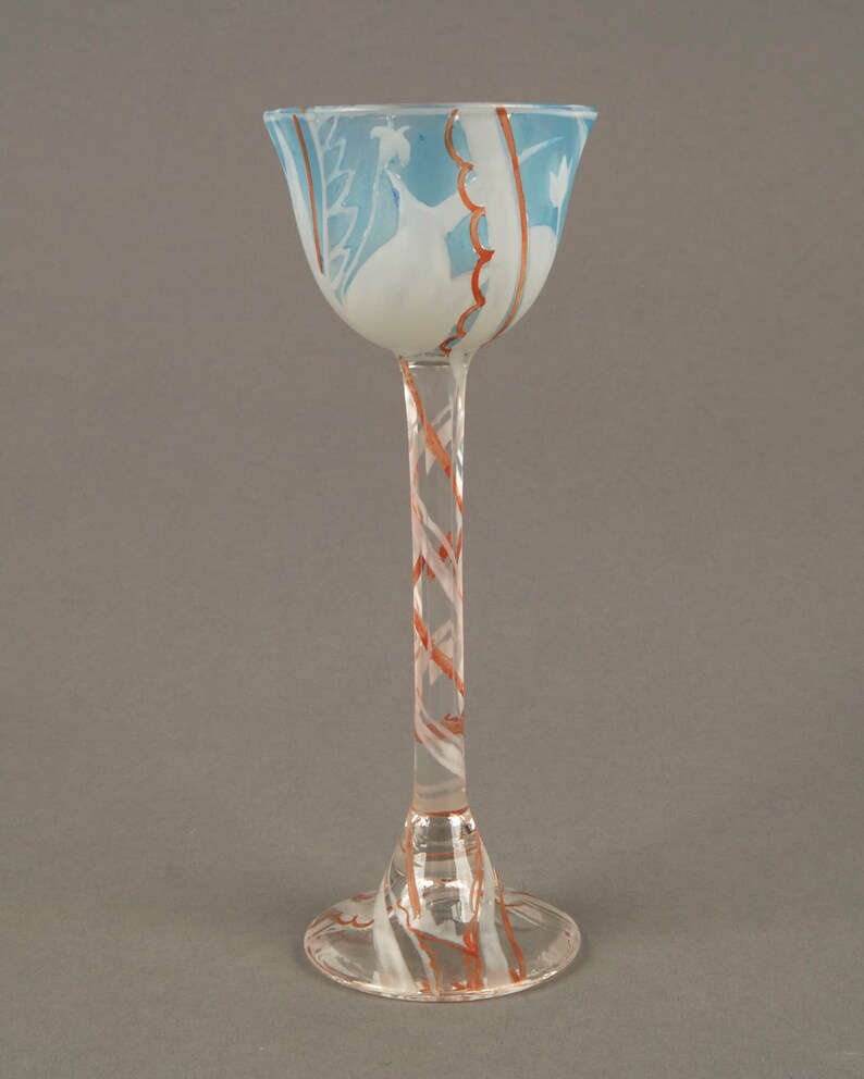 May include: A tall, clear glass goblet with a blue and white design on the bowl and a red and white swirl pattern on the stem and base.