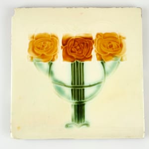 May include: A white ceramic tile with a decorative design of three orange roses in a green vase. The vase has a stylized Art Nouveau design.