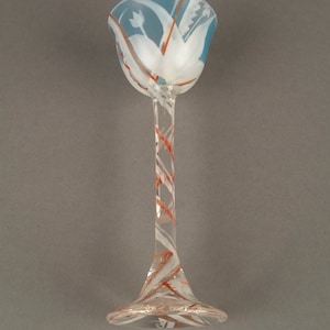 May include: A clear glass goblet with a blue and white swirl design. The stem is twisted and has a red and white swirl design.