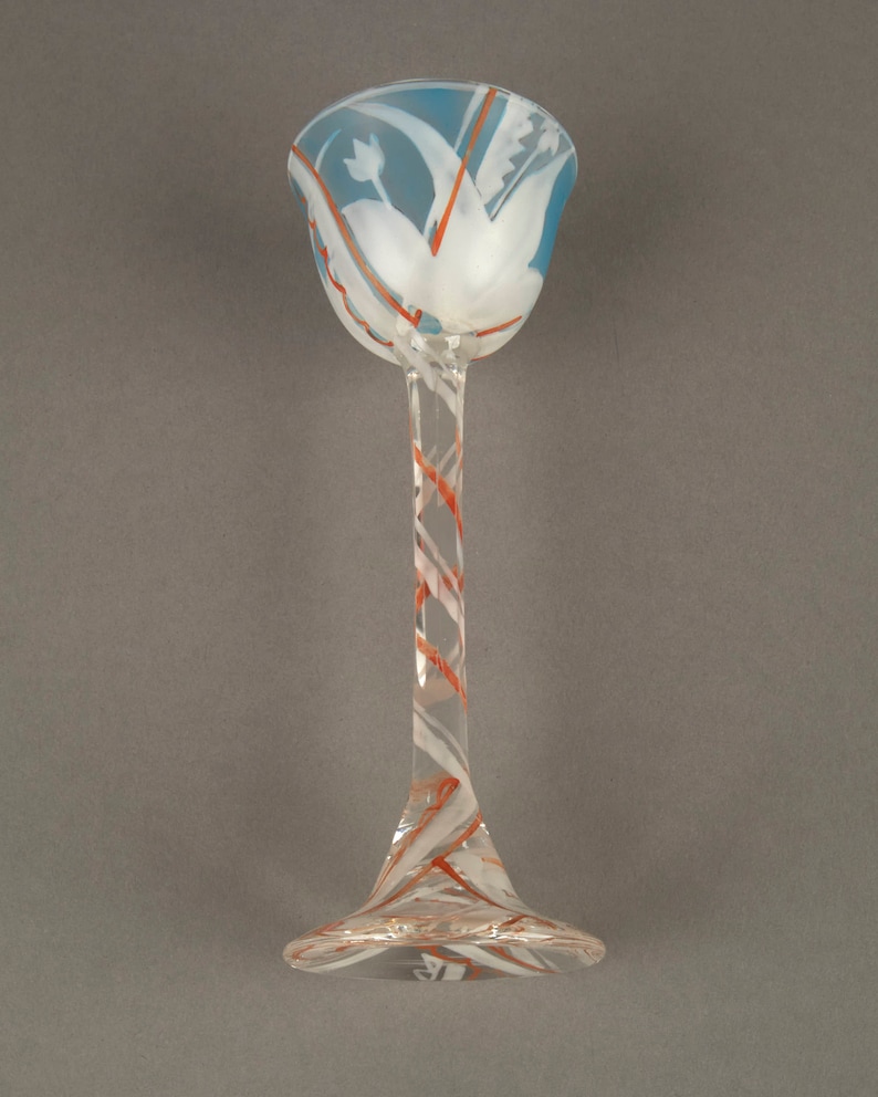 May include: A clear glass goblet with a blue and white swirl design. The stem is twisted and has a red and white swirl design.