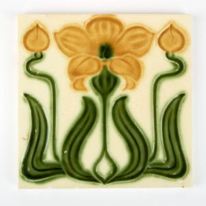 May include: Square ceramic tile with a floral design. The flower has yellow petals and a green centre, with green stems and leaves against a cream background. The tile is likely for decorative use, possibly for a wall.