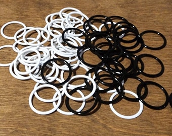 May include: A collection of white and black rubber O-rings. The O-rings are scattered on a wooden surface. The O-rings are circular and appear to be new.
