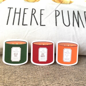 May include: Three candle jar stickers with a white background and the text "White Barn" on each. The candle jars are green, red, and orange. The text on the jars reads "Hello Fall", "Apple Harvest", and "Pumpkin Pie".