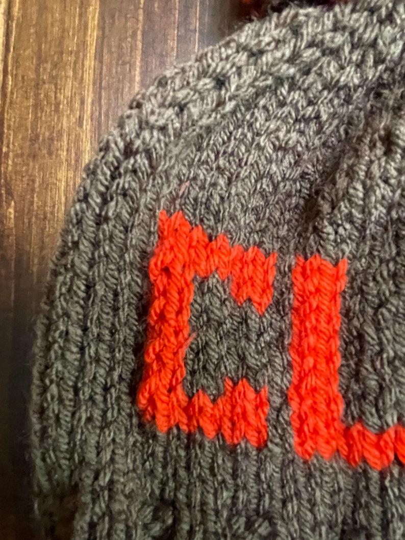 May include: A gray knitted hat with the letter "C" knitted in orange.