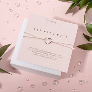 May include: White string bracelet with a silver heart charm and a card that reads "Get Well Soon" with a message of encouragement.