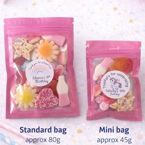 K&ouml;nnte beinhalten: Zwei wiederverschlie&szlig;bare rosa Plastikt&uuml;ten gef&uuml;llt mit bunten Fruchtgummis. Die gr&ouml;&szlig;ere T&uuml;te ist mit 'Thank you for celebrating Eleanor's 6th Birthday' beschriftet, die kleinere mit 'Thank you for celebrating Felicity's 5th Birthday'.