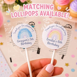 K&ouml;nnte beinhalten: Zwei runde Lutscherverpackungen mit Aquarell-Regenbogenillustrationen und Text. Einer lautet Thank you for celebrating Grayson's 5th Birthday, der andere Thank you for celebrating Emilia's 6th Birthday. Der Text Matching lollipops available steht dar&uuml;ber.