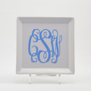 May include: A white square ceramic tray with a blue monogram of the letters "S W" in a script font.