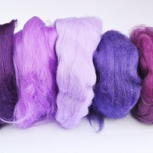 Puede incluir: Cinco madejas de lana cardada en tonos de morado, lavanda y rosa. La lana es suave y esponjosa, perfecta para fieltro o hilado.