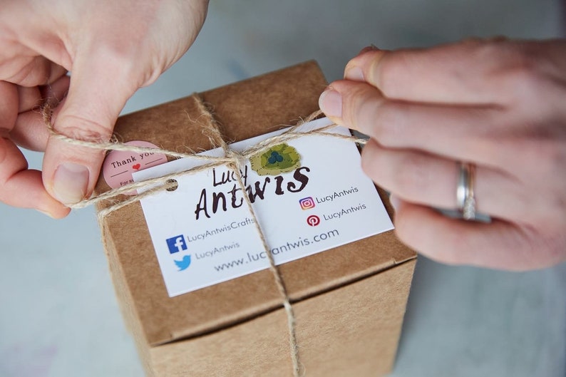 Puede incluir: Una caja de cart&oacute;n marr&oacute;n atada con cuerda y una etiqueta de regalo. La etiqueta tiene el texto "Lucy Antwis" y los iconos de redes sociales para Facebook, Twitter, Instagram y Pinterest. El texto "LucyAntwisCrafts" y "www.lucyantwis.com" tambi&eacute;n est&aacute;n en la etiqueta.