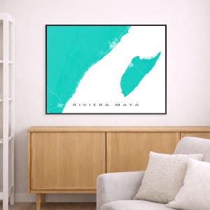 May include: A framed wall art print featuring a map of Riviera Maya in a vibrant teal color against a white background. The text "RIVIERA MAYA" is printed in black at the bottom. The artwork is displayed above a wooden cabinet.