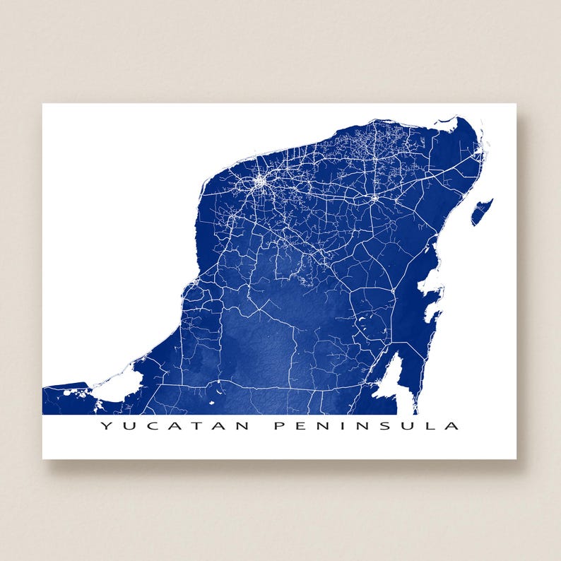 May include: A blue and white map print of the Yucatan Peninsula. The map features a detailed depiction of roads and infrastructure in white against a blue background. The words "YUCATAN PENINSULA" are printed in black at the bottom.