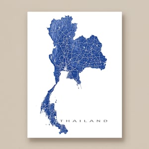 Könnte beinhalten: Eine blau-weiße Karte von Thailand, die die Form des Landes und sein Straßennetz zeigt. Das Wort "THAILAND" ist in einer Serifenschrift am unteren Rand des Bildes gedruckt. Die Karte befindet sich vor einem weißen Hintergrund.