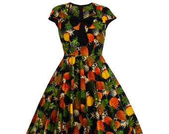 Puede incluir: Vestido negro con un estampado vibrante de piñas en tonos amarillos, naranjas y verdes. El vestido presenta un corpiño ajustado, una falda acampanada y un lazo negro en el escote. Mangas cortas.