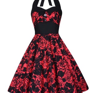May include: A knee-length halter dress featuring a vibrant red and black rose floral pattern. The bodice includes a solid black sweetheart neckline, a tie-neck halter strap, and two decorative buttons at the center. The skirt is flared.
