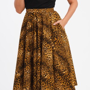 May include: A black top with a sweetheart neckline paired with a flared midi skirt featuring a leopard print pattern in shades of brown and black. The skirt has pockets.
