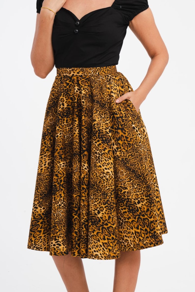 May include: A black top with a sweetheart neckline paired with a flared midi skirt featuring a leopard print pattern in shades of brown and black. The skirt has pockets.