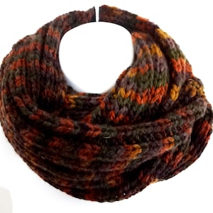 May include: A brown, orange, and green knitted infinity scarf. The scarf is made of a soft, chunky yarn and has a textured knit.