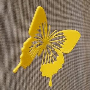 May include: A yellow butterfly-shaped cutout, with intricate details, is attached to a screen door.