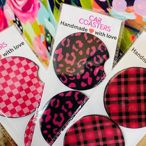 May include: Set of six car coasters with various patterns. The coasters are round and feature pink and black checkered, pink and black leopard print, and pink and black plaid designs. The coasters are handmade with love.