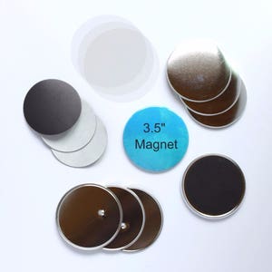 May include: A set of 3.5 inch round button magnets. The set includes silver, black, and clear button magnets. The magnets are arranged on a white surface.