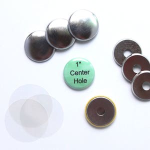 May include: An assortment of button-making supplies, including silver metal button shells, washers, and a green button with the text "1" Center Hole". Also included are clear plastic circles. The button with text is approximately 1 inch in diameter.