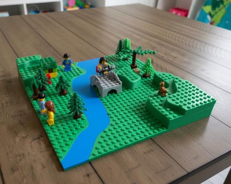 May include: A Lego diorama depicting a landscape with a river, bridge, trees, and figures. The base is green, with a blue river. Lego figures are placed throughout the scene, including a dog. The diorama is set on a wooden table.