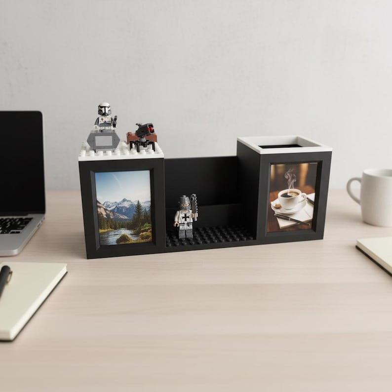 May include: A black desk organizer with a white interior, two photo frames, and a pen holder. The organizer is decorated with Lego figures and a landscape photo. One frame displays a photo of a cup of coffee.