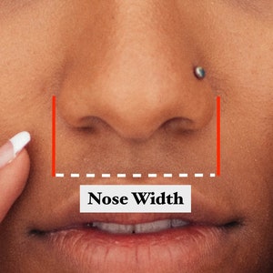Op de afbeelding: Close-up van een gezicht, met de nadruk op de neus en mond. Rode lijnen en een gestippelde witte lijn illustreren de meting van de neusbreedte. De tekst "Nose Width" wordt weergegeven in een witte rechthoek.