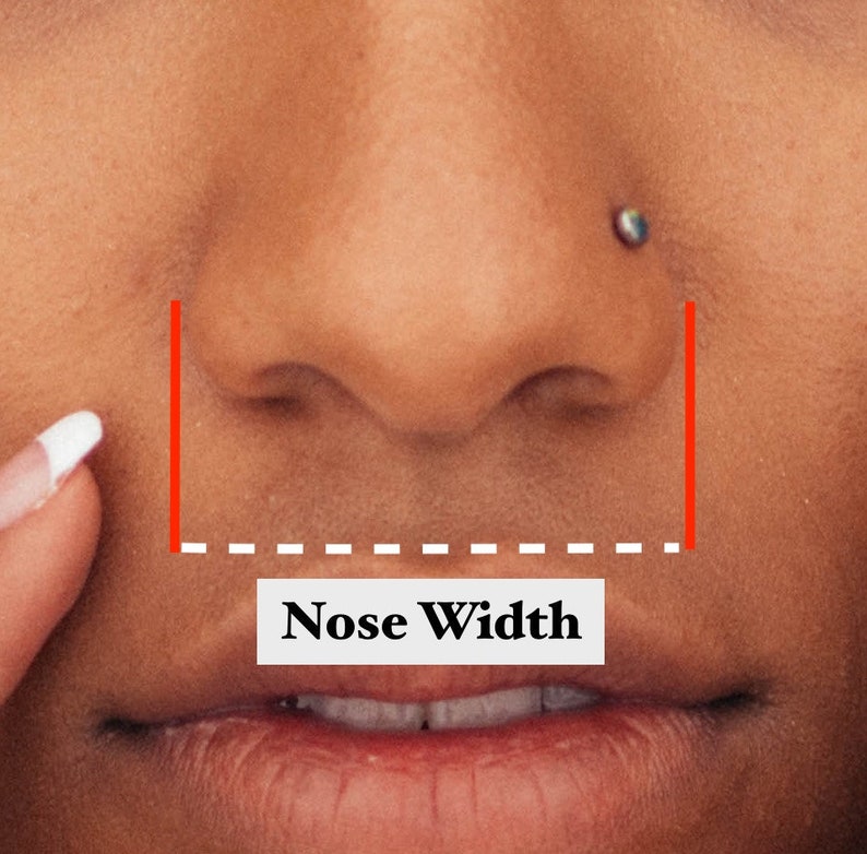 Op de afbeelding: Close-up van een gezicht, met de nadruk op de neus en mond. Rode lijnen en een gestippelde witte lijn illustreren de meting van de neusbreedte. De tekst "Nose Width" wordt weergegeven in een witte rechthoek.