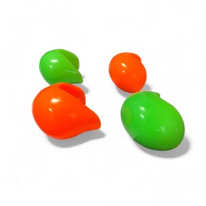 Può includere: Quattro oggetti lucidi a forma di goccia in colori vivaci. Due sono verde brillante e due sono arancione acceso. Gli oggetti sono disposti su uno sfondo bianco, proiettando ombre morbide.