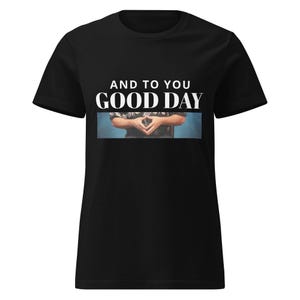 Può includere: T-shirt nero con la scritta bianca « AND TO YOU GOOD DAY ». La maglietta presenta un'immagine di mani giunte. La maglietta è in stile girocollo. Il design è semplice e pulito.