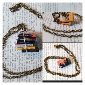 May include: Two gold chains with book-shaped charms. The charms are miniature versions of popular novels, including "The Red Rising" and "The Fourth Wing".